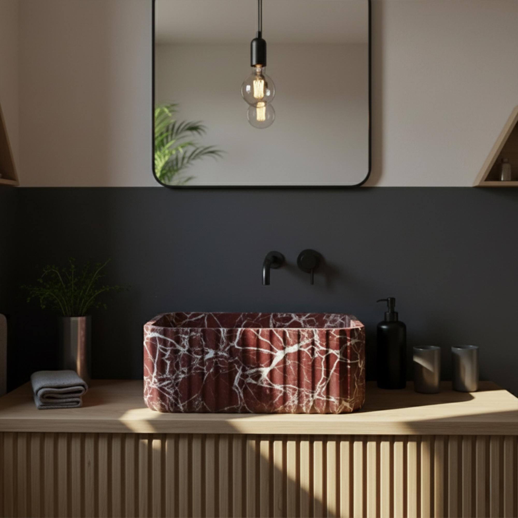 Dark red marble bathroom sink with vertical fluted design, set against minimalist black wall and wood vanity