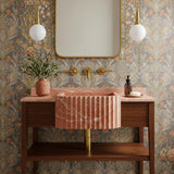 Hand-carved rose-toned marble sink with fluted apron design and integrated wood vanity base