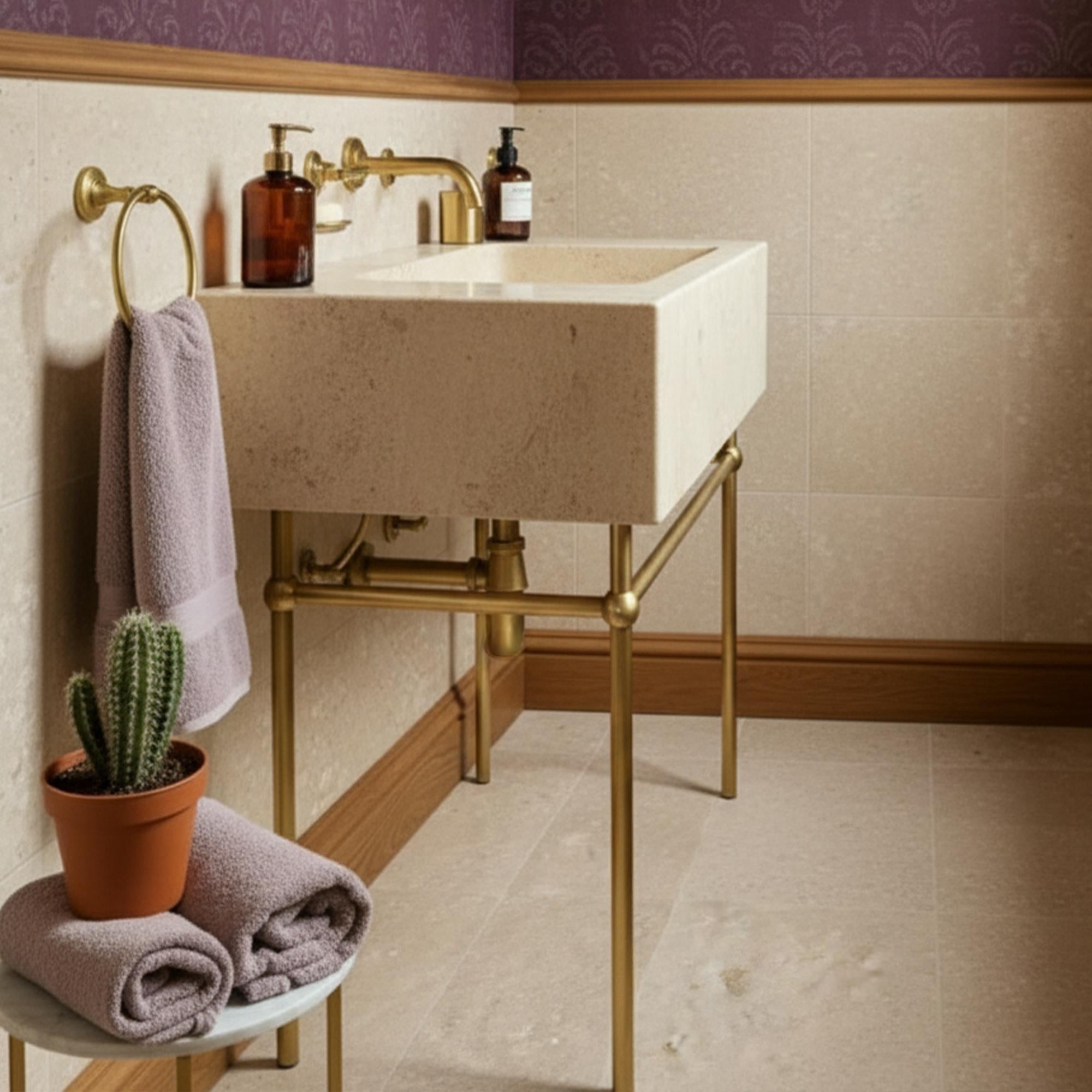 Wall-mounted stone vanity featuring a sculpted travertine basin and golden fixtures.